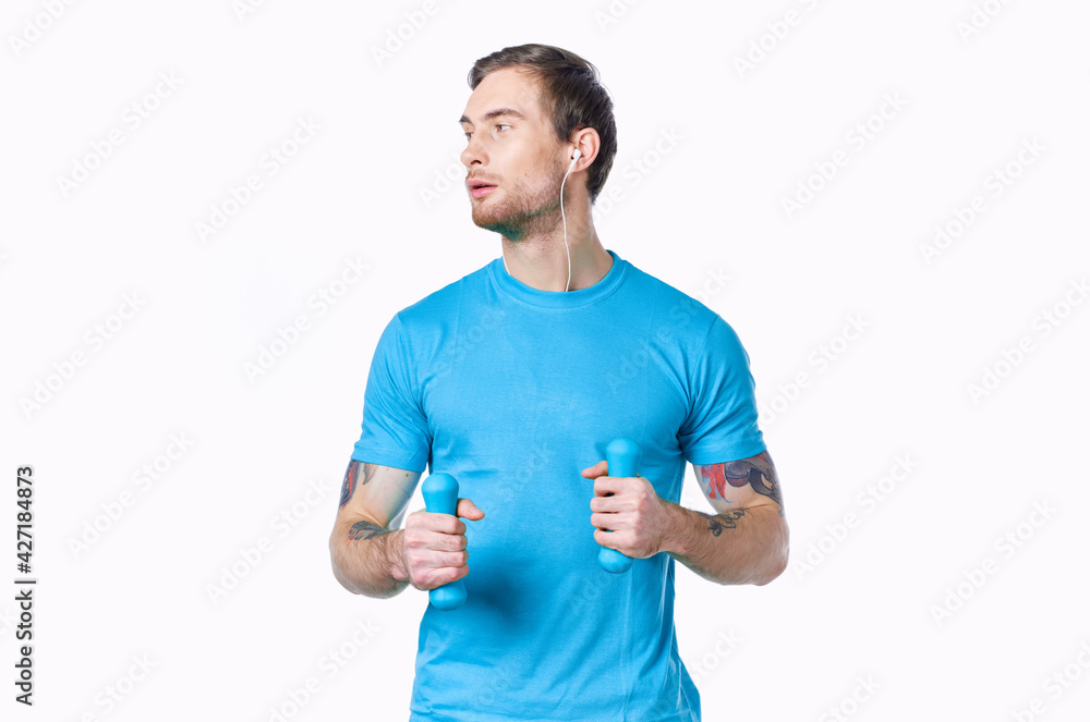man with dumbbells in a blue t-shirt on a light background looking to the side cropped view man with dumbbells in a blue t-shirt on a light background looking to the side cropped view