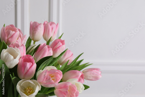 Beautiful bouquet of tulips against white wall  closeup. Space for text