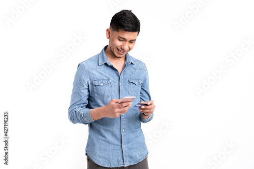 Latin man with with credit card and mobile phone buying online on white background photo