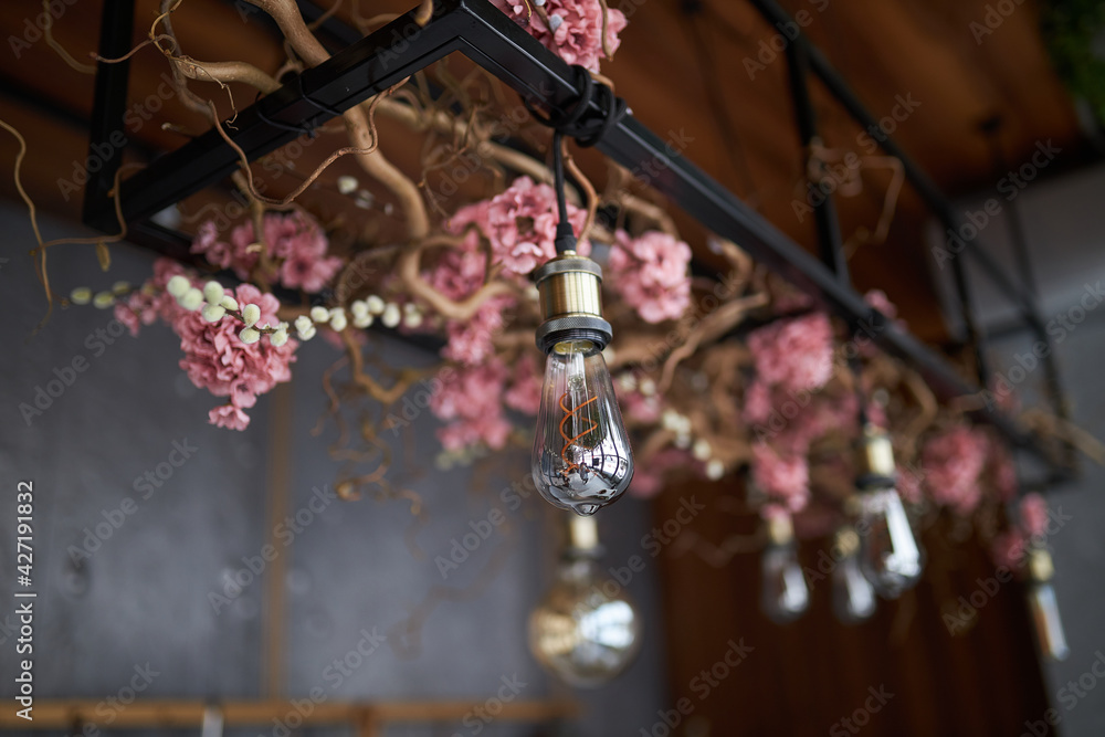 Home decor. Decorated electric lamps. Multi-colored light bulbs and flowers on the ceiling.