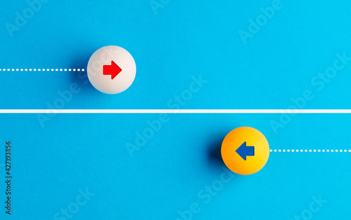 Arrow icons in contrast on table tennis balls moving towards opposite directions. photo