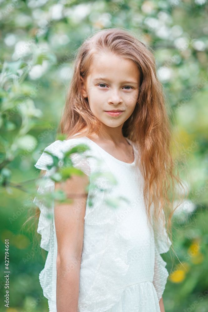Adorable little girl in blooming apple garden on beautiful spring day Adorable little girl in blooming apple garden on beautiful spring day
