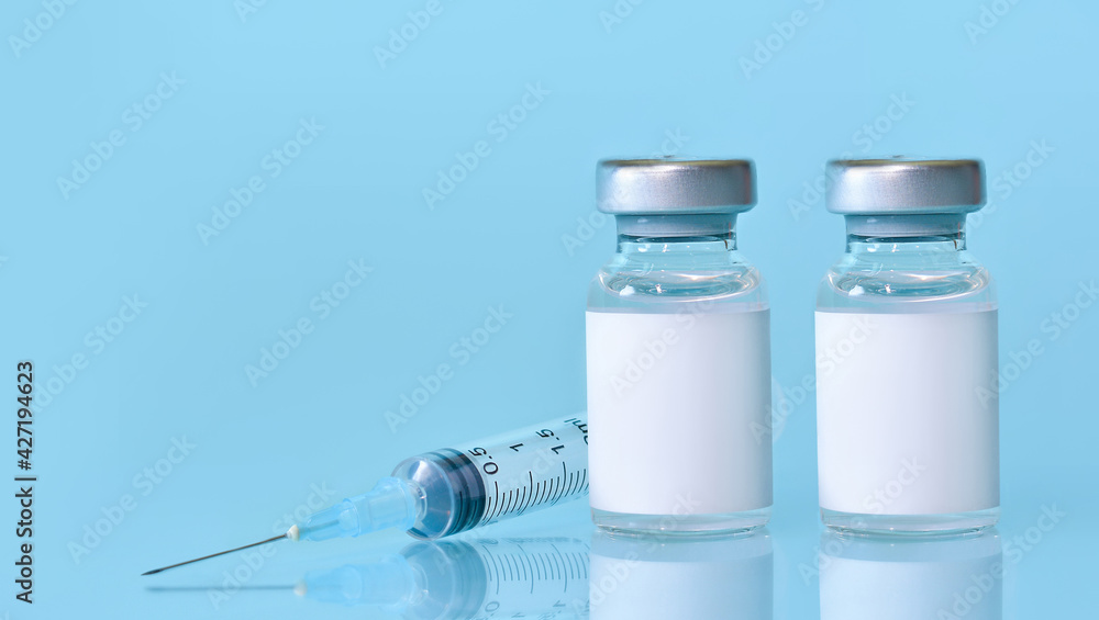 Two vials with a vaccine, a syringe on a blue background.The concept of medicine, healthcare and science.Coronavirus vaccine.Copy space for text. Two vials with a vaccine, a syringe on a blue background.The concept of medicine, healthcare and science.Coronavirus vaccine.Copy space for text.