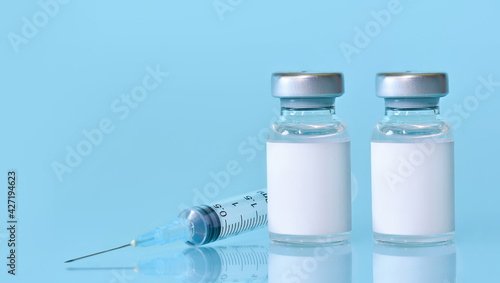 Two vials with a vaccine, a syringe on a blue background.The concept of medicine, healthcare and science.Coronavirus vaccine.Copy space for text.