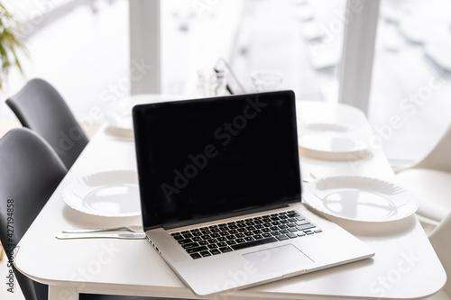 Laptop white screen on table with kitchen background.