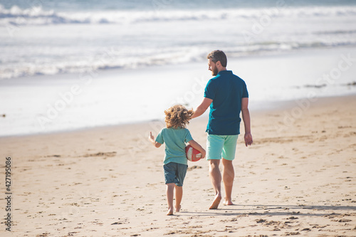 Dad and child having fun outdoors. Father and son walking on summer beach. Childhood and parenting concept.