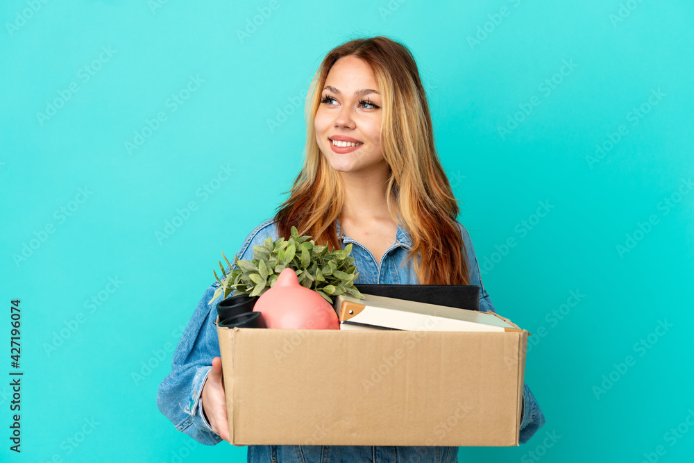 Teenager blonde girl making a move while picking up a box full of things looking side Teenager blonde girl making a move while picking up a box full of things looking side