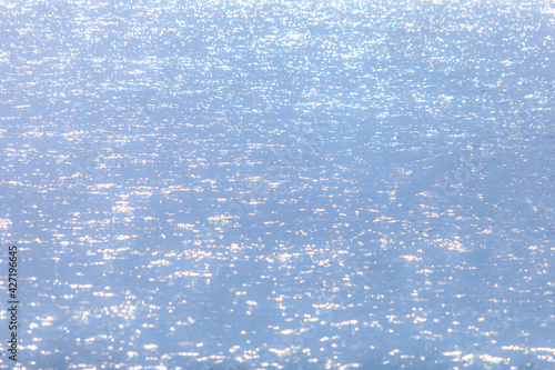 Soft sun light reflecting or sparkling glitter on water of sea or ocean with beautiful sky blue light tone.