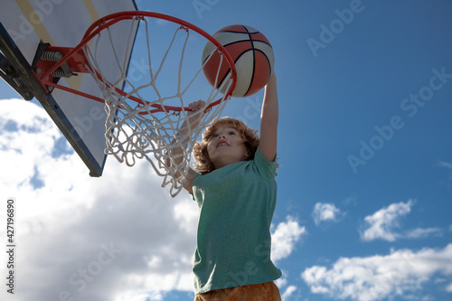Active kids enjoying outdoor game with basketball, outdoor on playground.