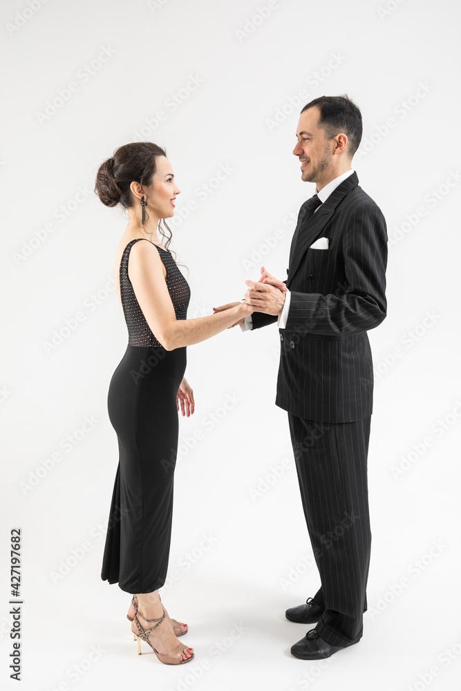 Couple of professional tango dancers in elegant suit and dress isolated on white background. Attractive man tangoniero invites the woman to dance