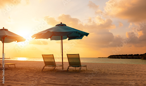 Sandy beach with deckchairs and umbrellas at sunset © JenkoAtaman