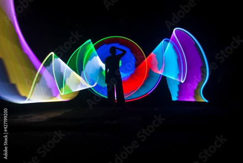 One person standing alone against beautiful color circle LED light painting as the backdrop © nafi