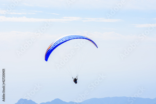 Paragliding in the sky. Paraglider tandem flying over the sea and mountains. Extreme sport
