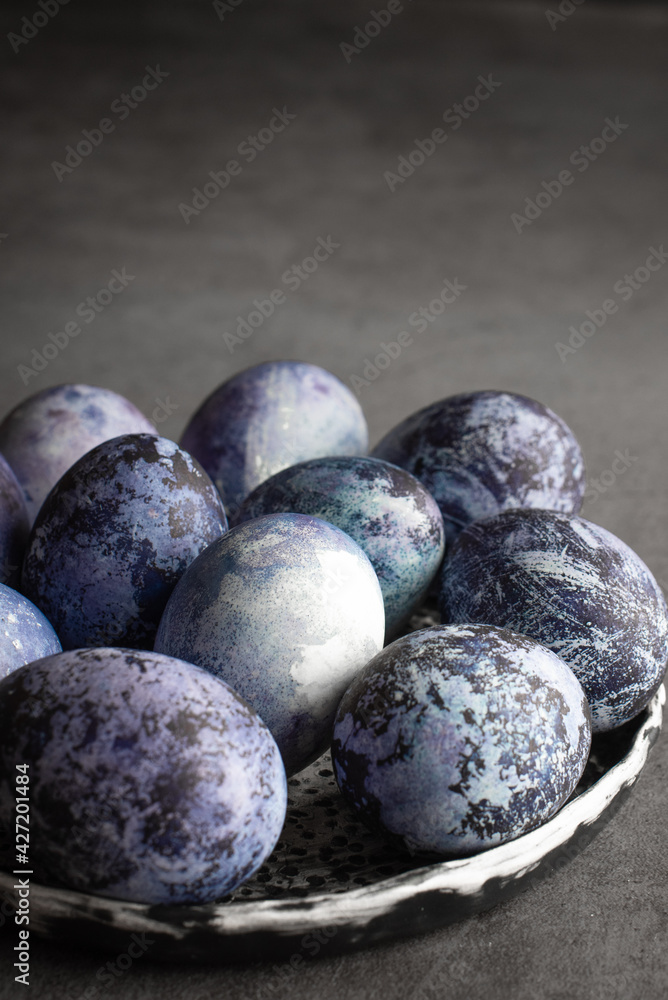 organic Easter eggs on a dark background, hand-painted with natural blueberries, lie in a clay cup on a stone table. Easter concept. organic Easter eggs on a dark background, hand-painted with natural blueberries, lie in a clay cup on a stone table. Easter concept.