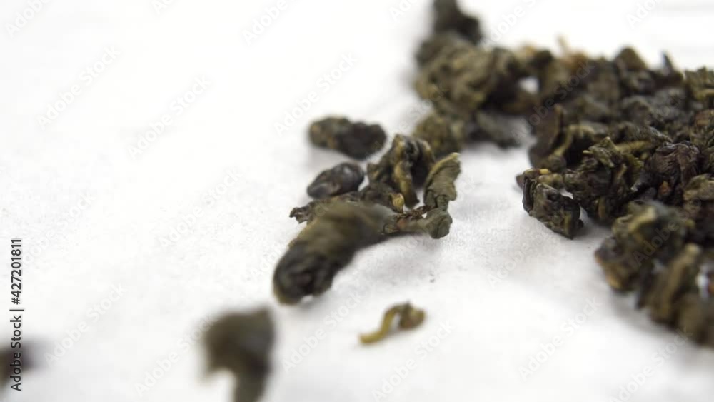 Pearls of green dried fermented Chinese oolong tea fall on a white paper napkin in slow motion. Macro. Dolly Shot Pearls of green dried fermented Chinese oolong tea fall on a white paper napkin in slow motion. Macro. Dolly Shot