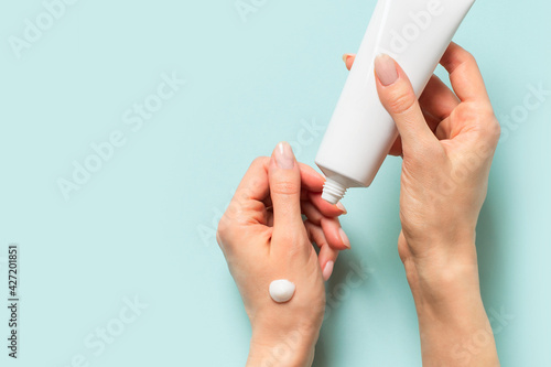 Beauty concept with woman hand and cream tube on blue background