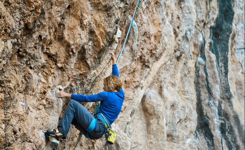 sports woman rock climber climbing on cliff, focused on difficult route and next move photo