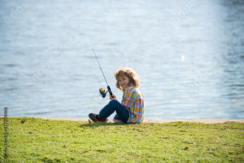 Kids hobby. Child fishing on the lake. Boy with spinner at river. Portrait of excited boy fishing. Boy at jetty with rod.