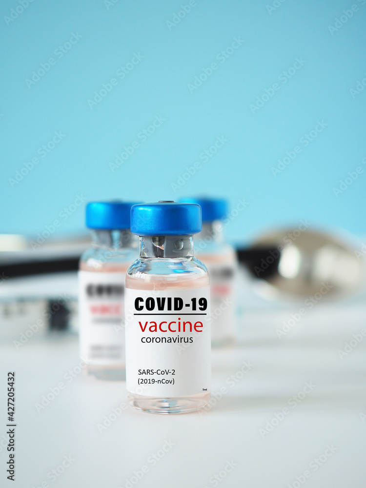 Close-up of a simulated Covid-19 vaccine in a vial for protective coronavirus on white background with a blue backdrop. Healthcare and medical concept.