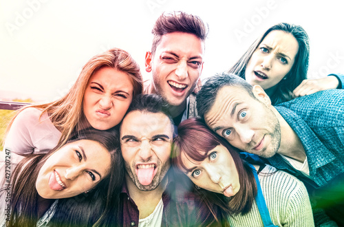 Multicultural millenial friends taking selfie with funny faces - Happy youth friendship concept with millennial young trendy people having fun together with tongue out -  Bright multicolor filter
