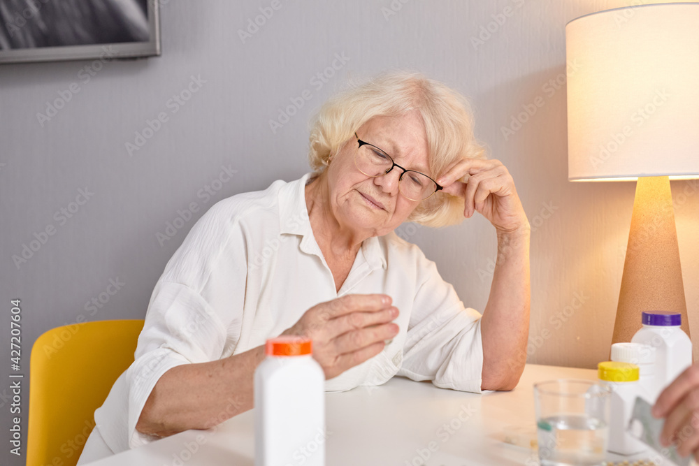 elderly woman with drugs in hands reading prescription of medication, sitting alone at home elderly woman with drugs in hands reading prescription of medication, sitting alone at home