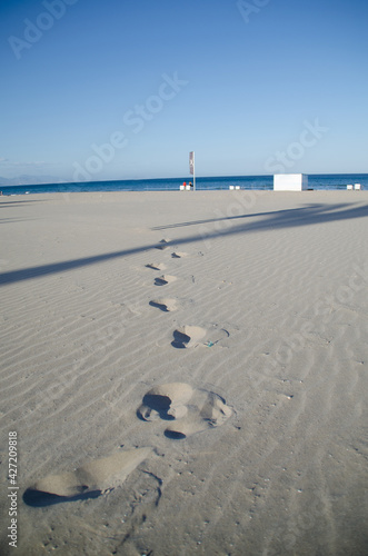 footprints on a clean white sand beach with the sea in the background