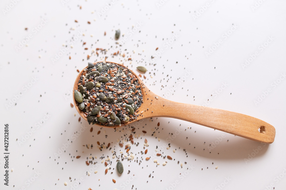 A wooden spoon with edible seeds on a white kitchen table A wooden spoon with edible seeds on a white kitchen table