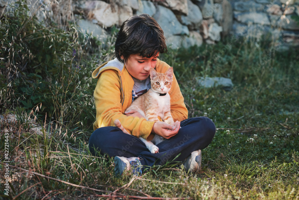 kid sitting on the grass with his kitten kid sitting on the grass with his kitten