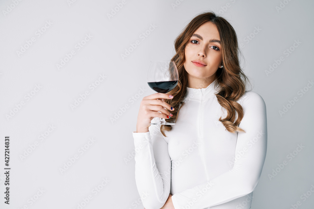 Pretty fashion woman holding glass of red wine on white background with copy space Pretty fashion woman holding glass of red wine on white background with copy space