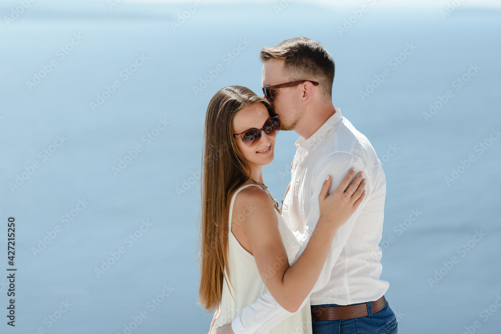 Happy couple hugging and laughing together with a view of Santorini