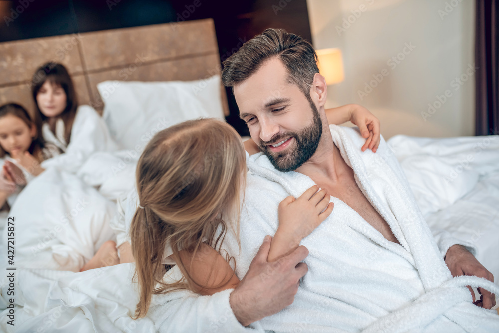 Young bearded man looking happy playing with his daughter Young bearded man looking happy playing with his daughter