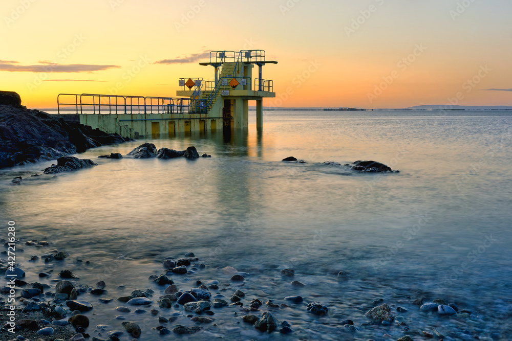 Beautiful morning orange sunrise scenery at Blacrock diving tower on Salthill beach in Galway, Ireland