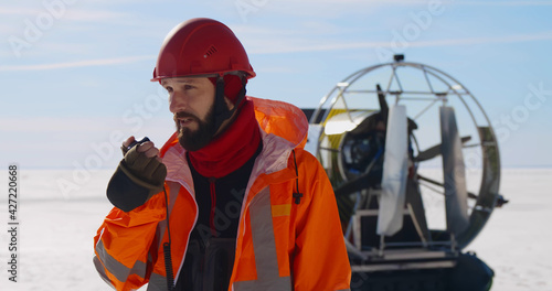 Portrait of bearded coast guard member talking on portable radio standing on frozen lake in winter