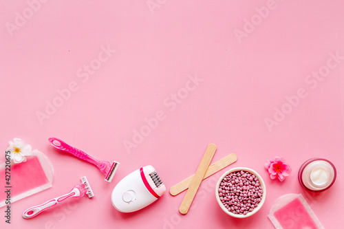 Cosmetics and means for epilation with flowers on pink background, flat lay