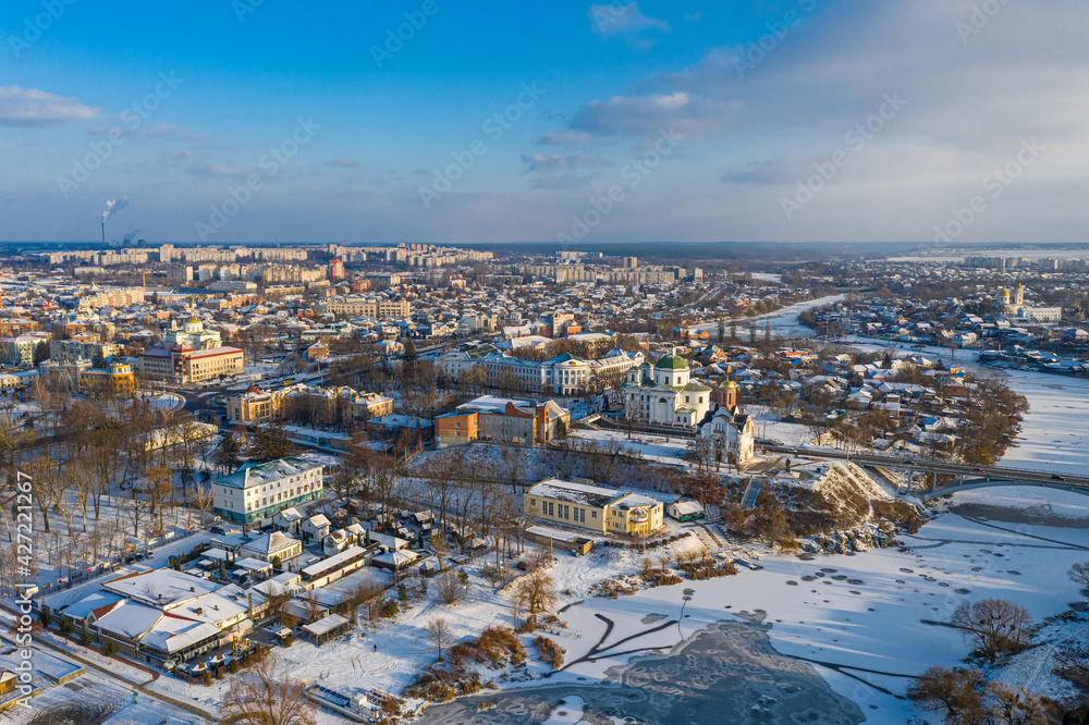 Nice top view of the winter city. Houses and buildings in the snow. Bridge over river. Orthodox churches and a Catholic cathedral. The river is covered with ice. Nice top view of the winter city. Houses and buildings in the snow. Bridge over river. Orthodox churches and a Catholic cathedral. The river is covered with ice.