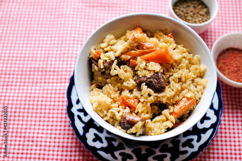 Bowl of asian food pilaf with rise, carrot and spices at table  background