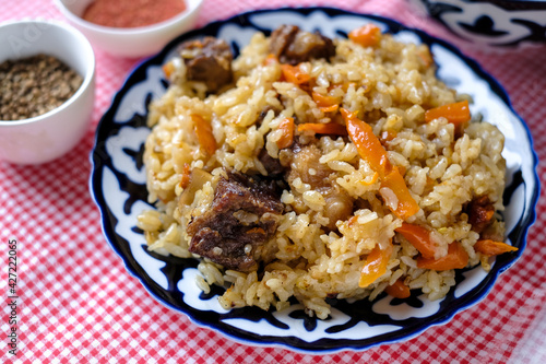 Bowl of asian food pilaf with rise, carrot and spices at table  background