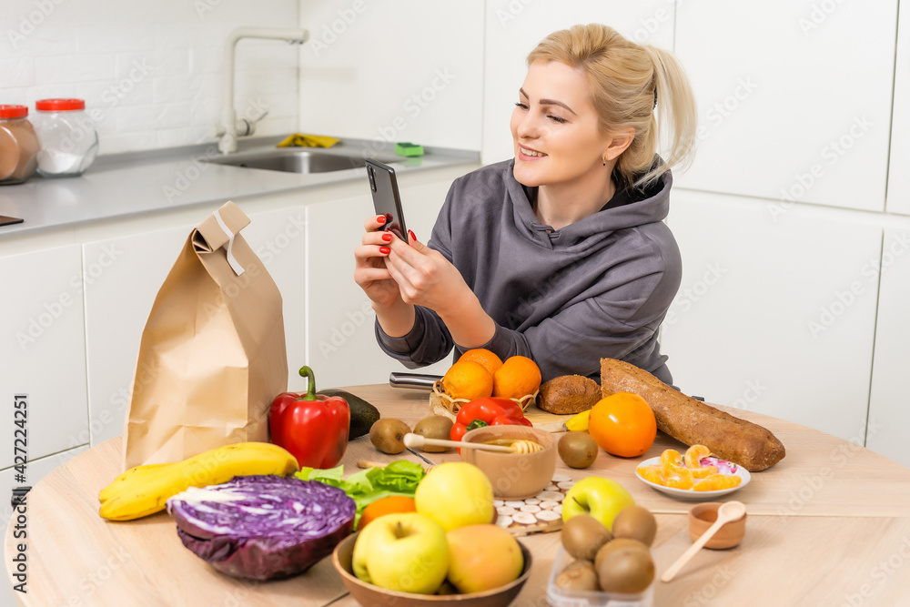 Woman sorts out purchases in the kitchen. Grocery delivery in paper bags. Subscription service from grocery store in conditions of quarantine because of coronavirus COVID19