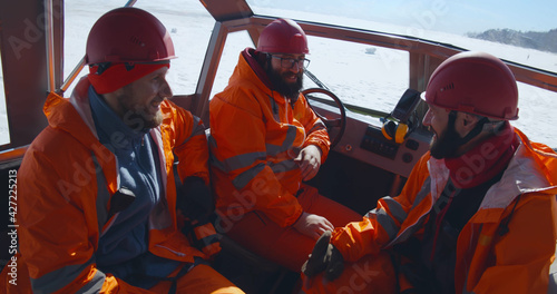 Professional rescuers in orange uniform sitting in boat and talking photo