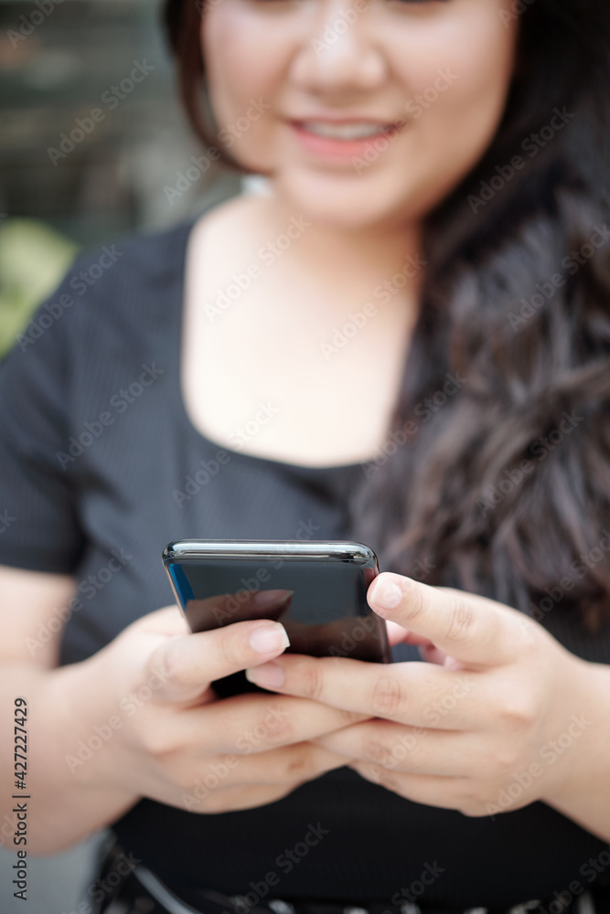 Close-up image of young woman using application on smartphone or texting friends Close-up image of young woman using application on smartphone or texting friends
