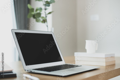 Interior of modern cozy contemporary work space corner with laptop, book, pen and tree on a wooden table. It is a working corner that is set up for working at home. 3d rendering