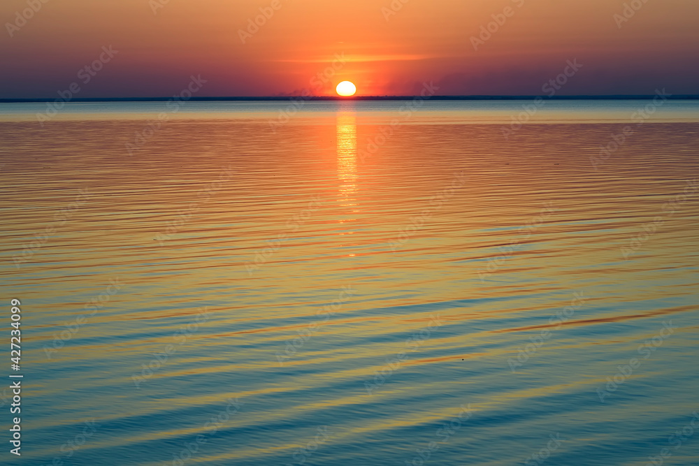 Bright beautiful sunset at the calm sea. Solar disk over water.