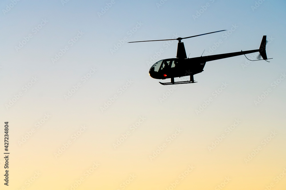 Fototapeta premium Silhouette of a helicopter on the background of the evening sky.