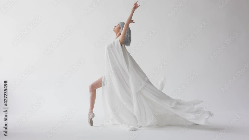 Beautiful graceful female ballet dancer dancing in long white dress practicing ballet in dance studio. Ballerina dancing on white background, working on herself. Professional choreography, art. Beautiful graceful female ballet dancer dancing in long white dress practicing ballet in dance studio. Ballerina dancing on white background, working on herself. Professional choreography, art.