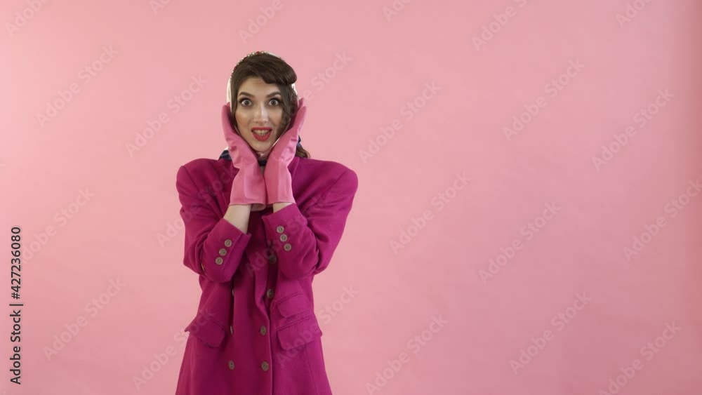 A stylish woman with bright makeup in rubber gloves is surprised and looks at the camera. The concept of a home routine. Daily chores around the house. Pin-up style. A stylish woman with bright makeup in rubber gloves is surprised and looks at the camera. The concept of a home routine. Daily chores around the house. Pin-up style.
