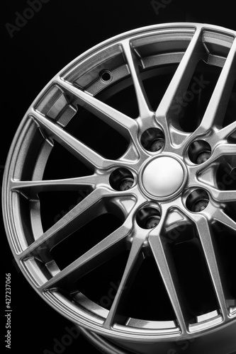 sporty lightweight alloy wheel, spokes and rim close-up on a black background, close up vertical photo