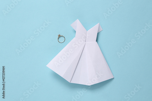 Origami wedding dress and wedding ring on blue background © splitov27
