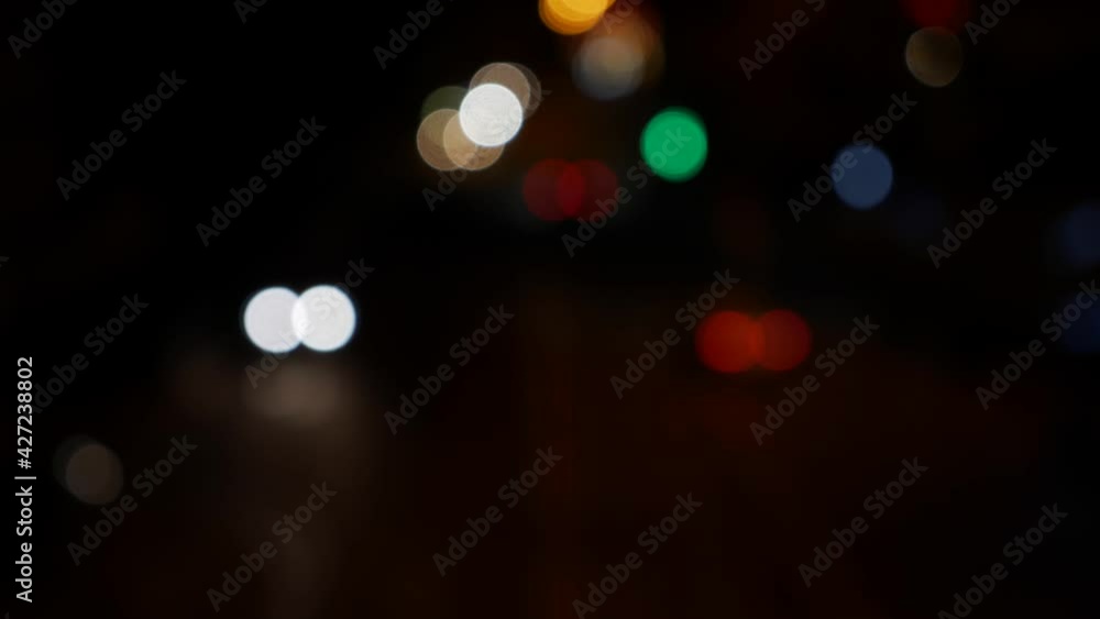 Beautiful glittering bokeh in dark blurry background at night. The round colorful bokeh shine from car lights on city street. Out of focus with blurry. Unfocused city lights. Traffic bokeh. Abstract