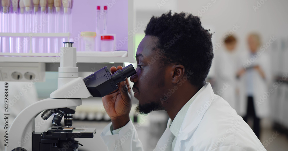 African-american man making medical research using microscope working in lab African-american man making medical research using microscope working in lab