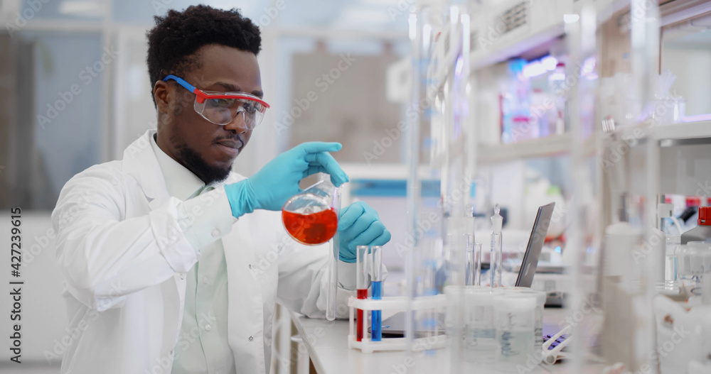African chemistry researcher in sterile laboratory using modern